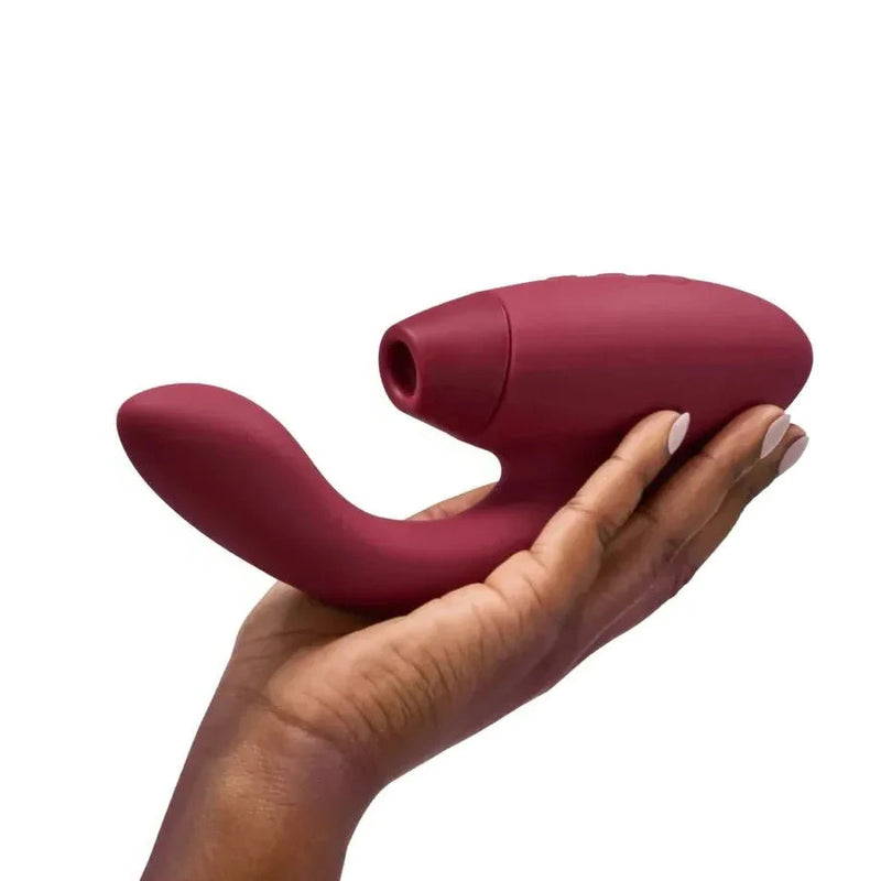 Red vibrator held in a hand on a white background
